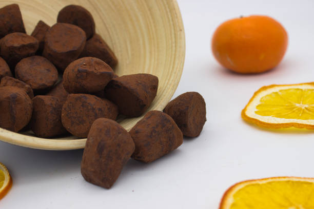 Chocolate truffles with orange accents on bamboo plate