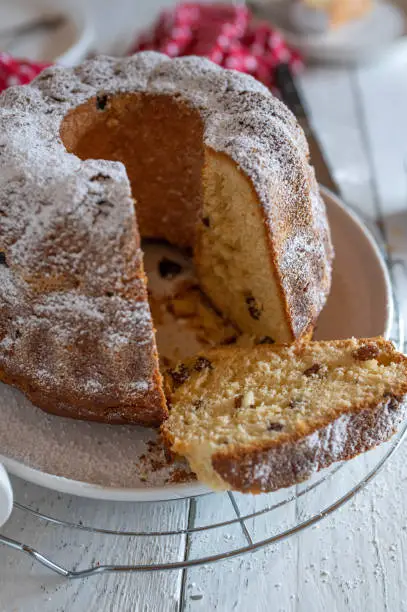 Traditional german gugelhupf or yeast bundt cake with raisins. Served open and ready to eat on a white wooden table background.