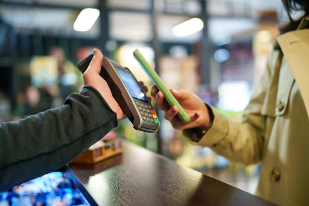 Young Asian Woman Mobile Paying in Bookstore Checkout.
