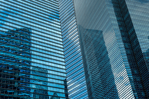 closeup contemporary glass and metal skyscraper facade, dominating frame in shades of blue. Perfect backdrop for financial and business advertising, showcasing modern, sophisticated architecture