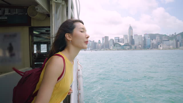 Young Asian woman looking out through the window while traveling by ferry at Victoria Harbour