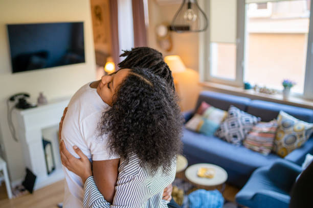 A couple canoodling in the lounge Giving each other a close hug, a young African-American married couple are embracing while standing in a lounge in their apartment canoodling stock pictures, royalty-free photos & images