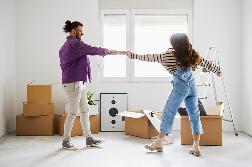 Couple dancing  in their new apartment. They had just moved in. Everything is still packed in cardboard boxes