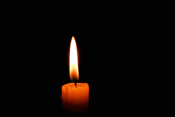 istock Candle flame on black background. Single lit candle with quite flame. Dramatic burning candle flame on a black background with copy space 2020472752