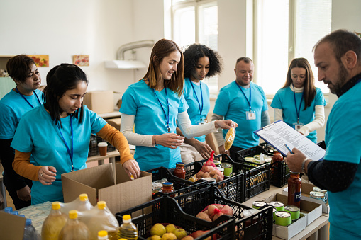 A large group of young adults volunteering their time for service in their community, organizing food donations for distribution for disadvantaged people