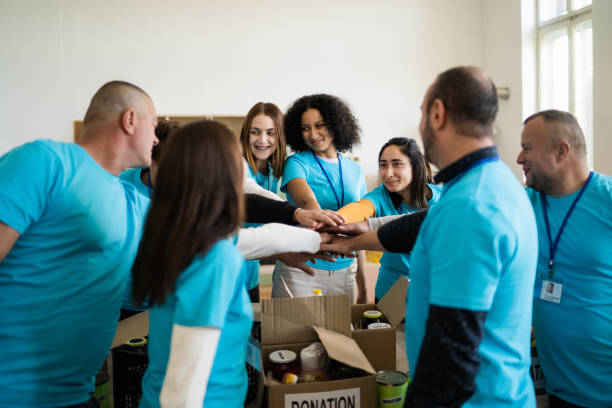 istock Side view of a group of aid workers with outstretched arms touching each others hands 2020482376