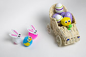 Lilac Easter eggs and small toys bunnies birds in a toy wicker car. The concept of Easter