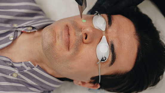 Man undergoing light peel treatment in beauty clinic