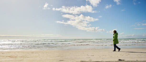 istock Mature woman walking alone on a sandy beach on a cool day 2020517001