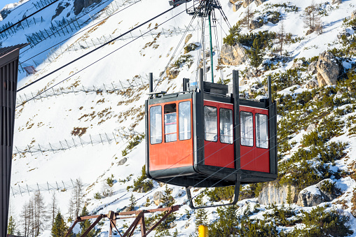 Detail of an aerial tramway passenger cabin approaching the lower station in the Alps on a sunny winter day. Dolomites, Italy.