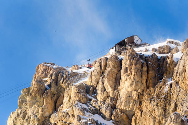 overhead cable car cabin approaching a mountaintop station on a clear and windy winter day - overhead cable car dolomites italy snow imagens e fotografias de stock