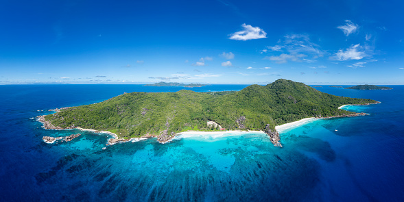 Tropical beach shot from a drone waves hitting the white sandy beach with corals rocks and lagoon - aerial series seychelles