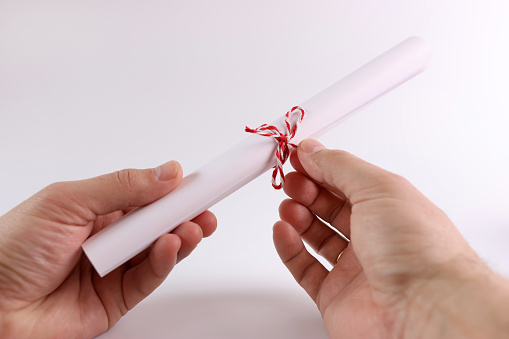 The paper is twisted into a tube and tied with a thread. The concept of a handwritten scroll, a document.