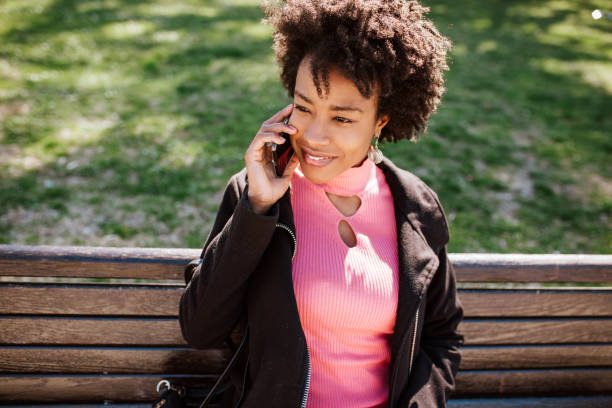 istock Young black woman using phone in a park 2020594124