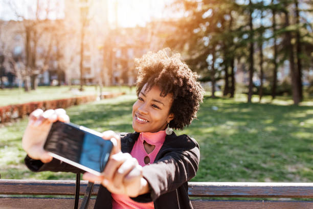 istock Young black woman using phone in a park 2020594647