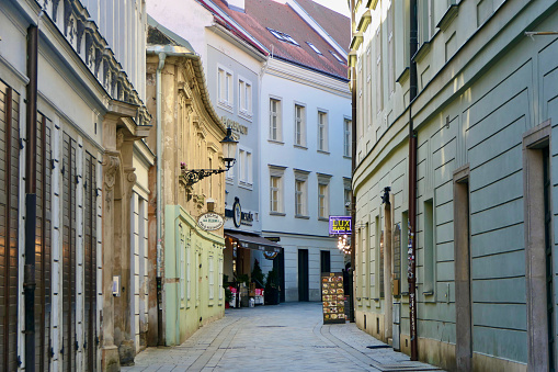 This relatively narrow alley in Old Town, Bratislava, displays the ornate architectural style, pastel colors of the building facades and red roofing typical of the area.