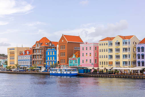 Curacao. Willemstad. 02.18.2024. Stunning vista of vibrant houses in the heart of Willemstad, overlooking St. Anna Bay with backdrop of cloudy sky.