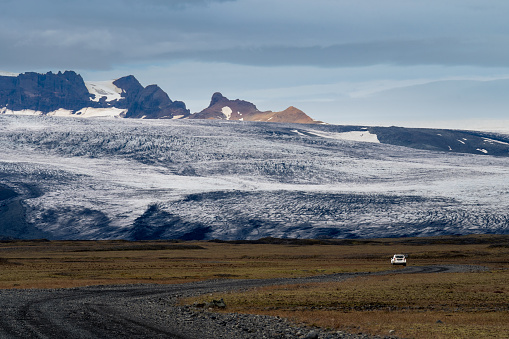 Car driving on gravel road in Iceland - view of Icelandic nature and mountains, glacier and Vatnajökull National Park, Iceland