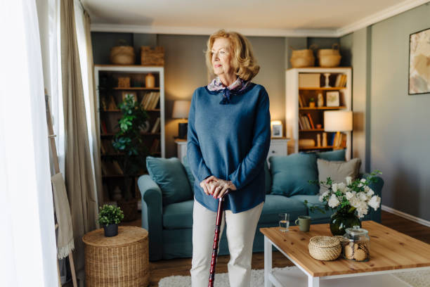 istock Senior woman standing by a window with a cane 2020627114