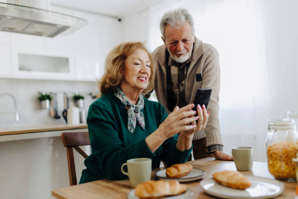 istock Elderly couple using mobile phone over breakfast at home 2020631421