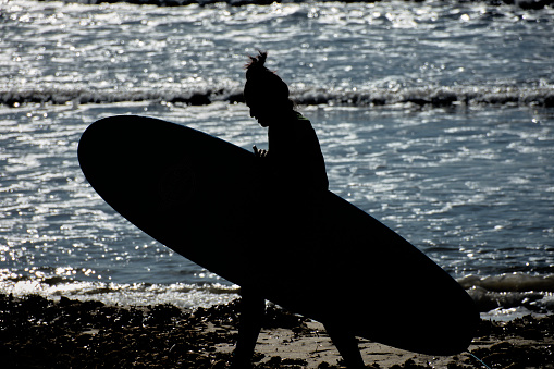 The silhouette of a surfer leaving after a hard day walking along the Arenal beach in Mallorca