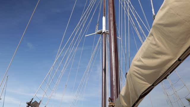 A large vintage wooden yacht sails on the sea. View of the bow of the yacht with furled sails. Pullesy and ropes details Shrouds and ropes close-up of an old sailboat. High quality 4k footage