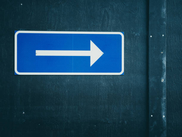 istock Blue Directional Arrow Sign Pointing Right on a Dark Wooden Wall 2020646572