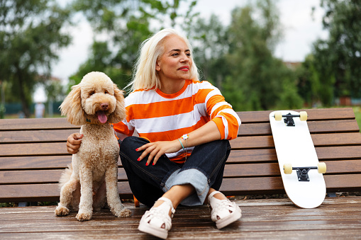 Mature adult happy woman enjoying with dog at skate park