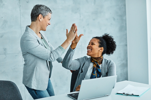 Portrait of two young businesswomen exchanging high five during a meeting in the office