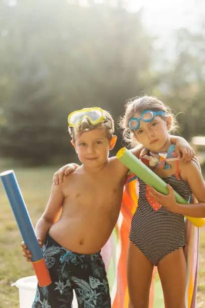 Group of children posing with squirt guns and prepare to have some fun in the yard with water fight on a hot summer day