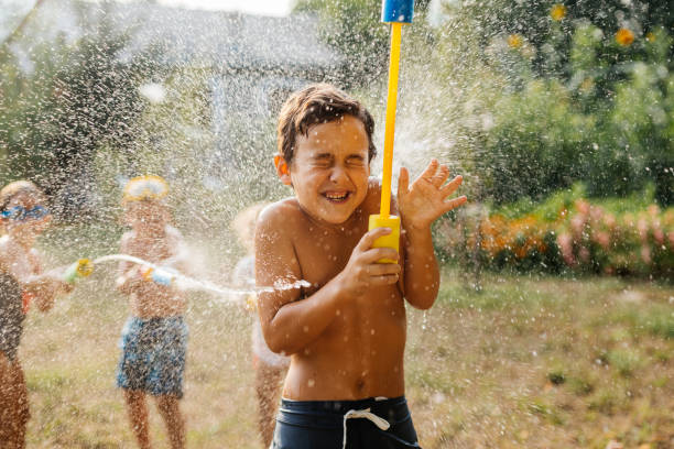 Children having fun spraying with water guns and enjoy refreshing on a hot summer day