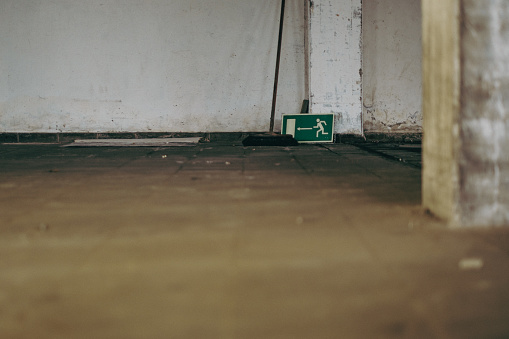Emergency exit sign on the floor in an empty old warehouse