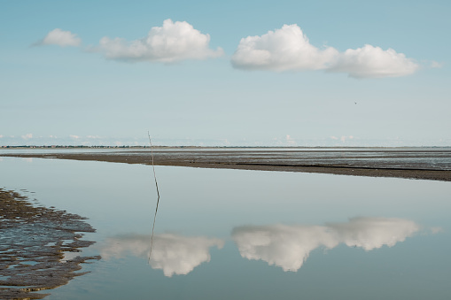 Clouds are reflected on the harbor entrance of an island in the Wadden Sea when there is absolutely no wind