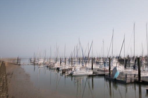 Blurred view of a boat harbor in the Wadden Sea with sailing boats as the water recedes