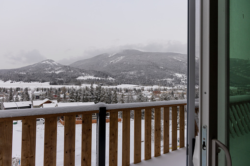 View past deck railing to mountains in snowy landscape