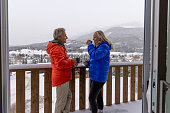 Mature couple enjoy hot beverage on deck in winter