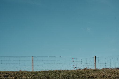 Chain link fence on a dike against a blue sky
