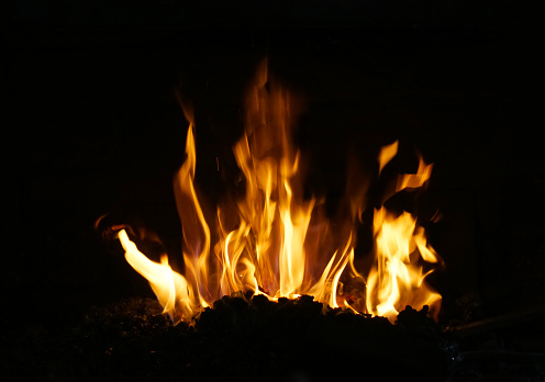 Stock photo showing large flames on a barbecue at an outdoor beach restaurant, which has been lit in preparation of cooking seafood.