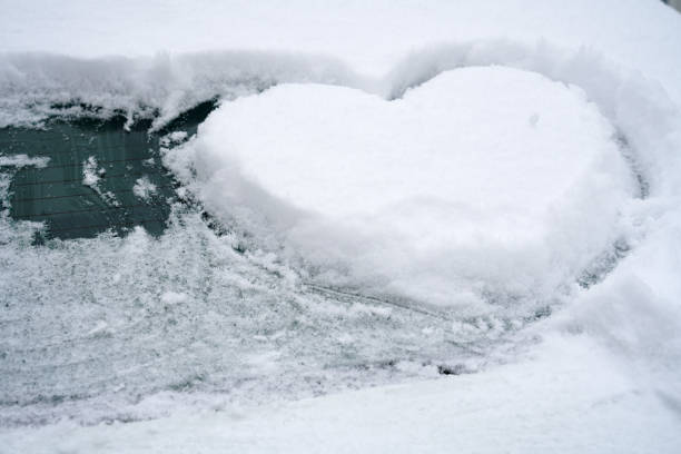 istock close up on drawing hearts on car windshield after snow 2020788361