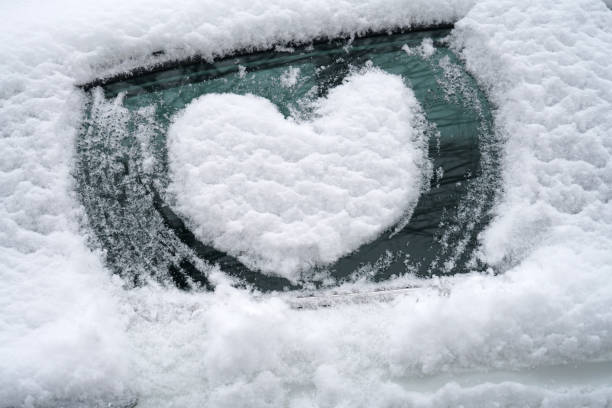 istock close up on drawing hearts on car windshield after snow 2020788801