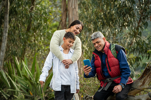 Grandfather showing cell phone to his children on ecological walk