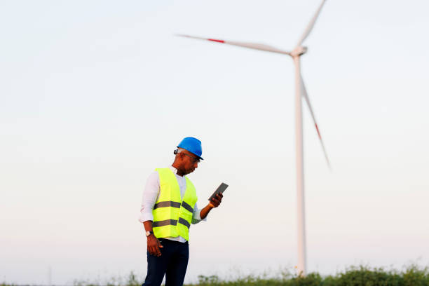 istock Young Engineer wearing uniform ,helmet hold document inspection work in wind turbine farms rotation to generate electricity energy. 2020824336