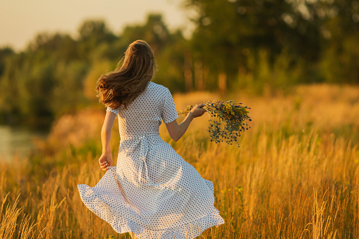 Blonde woman in dress running through meadow.