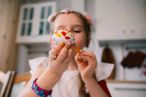 Little girl painting the egg , preparing for Easter at home. High quality photo