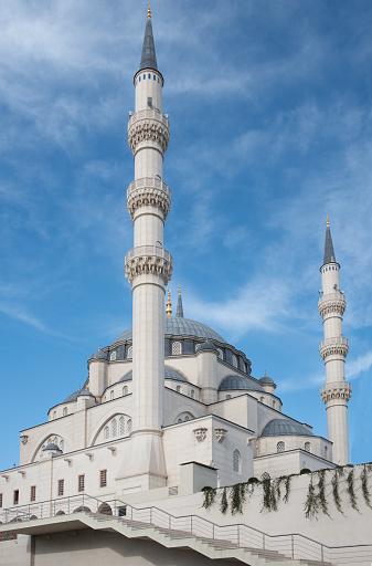 Close-up of the Namazgah Mosque in Tirana, Albania in portrait format. Two of the four towers can be clearly seen. The bright mosque lies in the blue sky.
