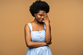 Timid African American woman hiding face confused look to camera isolated on beige studio background