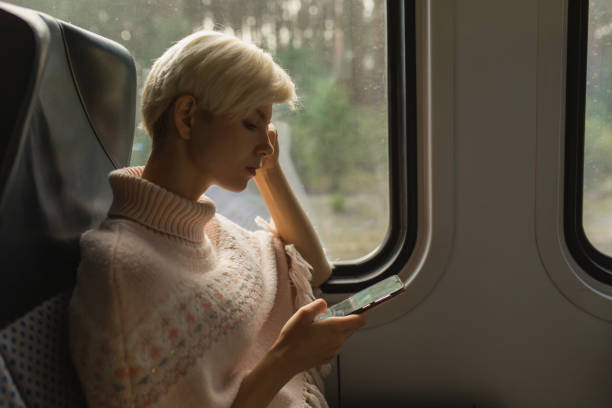 istock Blonde woman on train with mobile phone. Passenger 2020909085