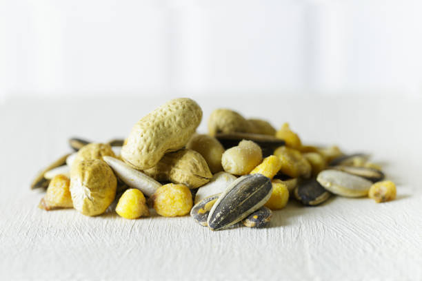Closeup of a pile of nuts, sunflower seeds, peanuts, pumpkin seeds, corn and chickpeas with salt. White background.