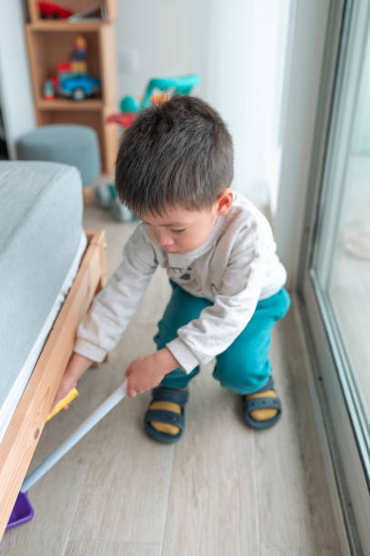 istock Two and a half year old boy joyfully sweeping the floor bellow the bed at home playing with chore activities 2020951462