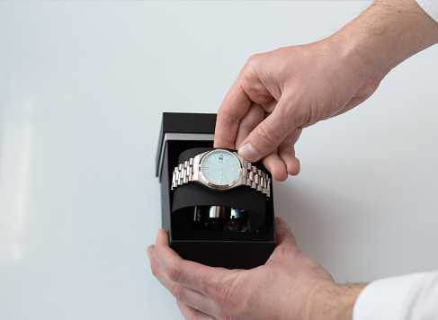 close up of man hands picking up taking a wrist watch from a box